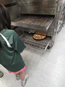 Avalanche Pizza owner helps a kid make pizza